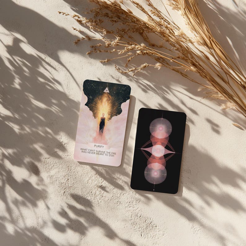 May include: Two tarot cards with celestial designs. One card features a figure in a bright light with the word "PURIFY" and the text "WHAT CAN'T SURVIVE THE FIRE WAS NEVER MEANT TO STAY." The other card has a black background with pink geometric shapes.