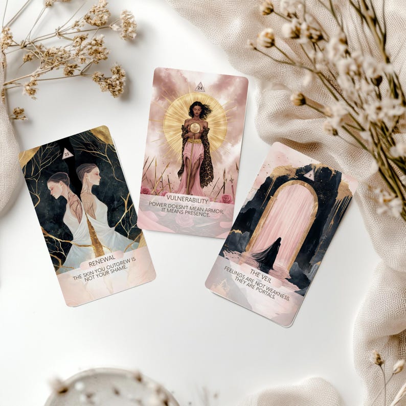 May include: Three tarot cards with illustrations and text. One card reads "Renewal," another "Vulnerability," and the third "The Veil." The cards feature gold accents and soft, pastel colors. Dried flowers and a white cloth surround the cards.