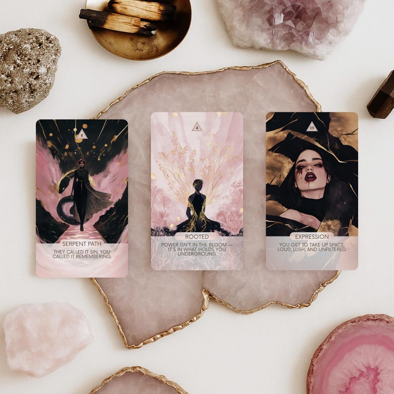 May include: Three tarot cards with pink and gold accents. The cards feature illustrations of figures and text. The first card reads "Serpent Path" and "They called it sin, you called it remembering." The second card reads "Rooted" and "Power isn't in the bloom - it's in what holds you underground." The third card reads "Expression" and "You get to take up space, loud, lush, and unfiltered."