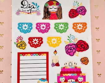 May include: A sheet of colorful stickers featuring a Day of the Dead theme. The stickers include a girl with a sugar skull face, flowers, candles, a cake, and a note pad. The text "Dia de los Muertos" is included on the sticker sheet.