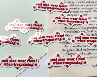 Könnte beinhalten: Eine Sammlung von Aufklebern mit dem Aufdruck "real men wear floral when trespassing". Die Aufkleber sind mit kleinen roten Blumen verziert.
