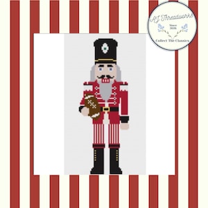 Peut inclure: Une figurine de casse-noisette en style pixel art portant un uniforme rouge et blanc avec un chapeau et des bottes noirs, tenant un ballon de football américain. Le motif présente un fond blanc à rayures rouges et un logo AJ Threadworks Since 2026.
