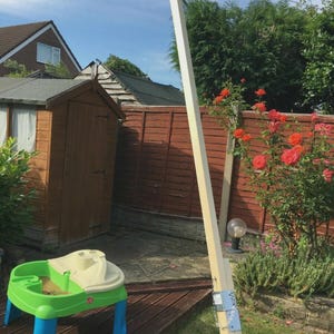 K&ouml;nnte beinhalten: Eine Gartenszene mit einer Holzspielstruktur und einem Sand- und Wassertisch. Die hellfarbige Holzstruktur ist mit Metallhalterungen befestigt. Der Tisch ist gr&uuml;n, blau und beige, perfekt f&uuml;r das Spielen im Freien.