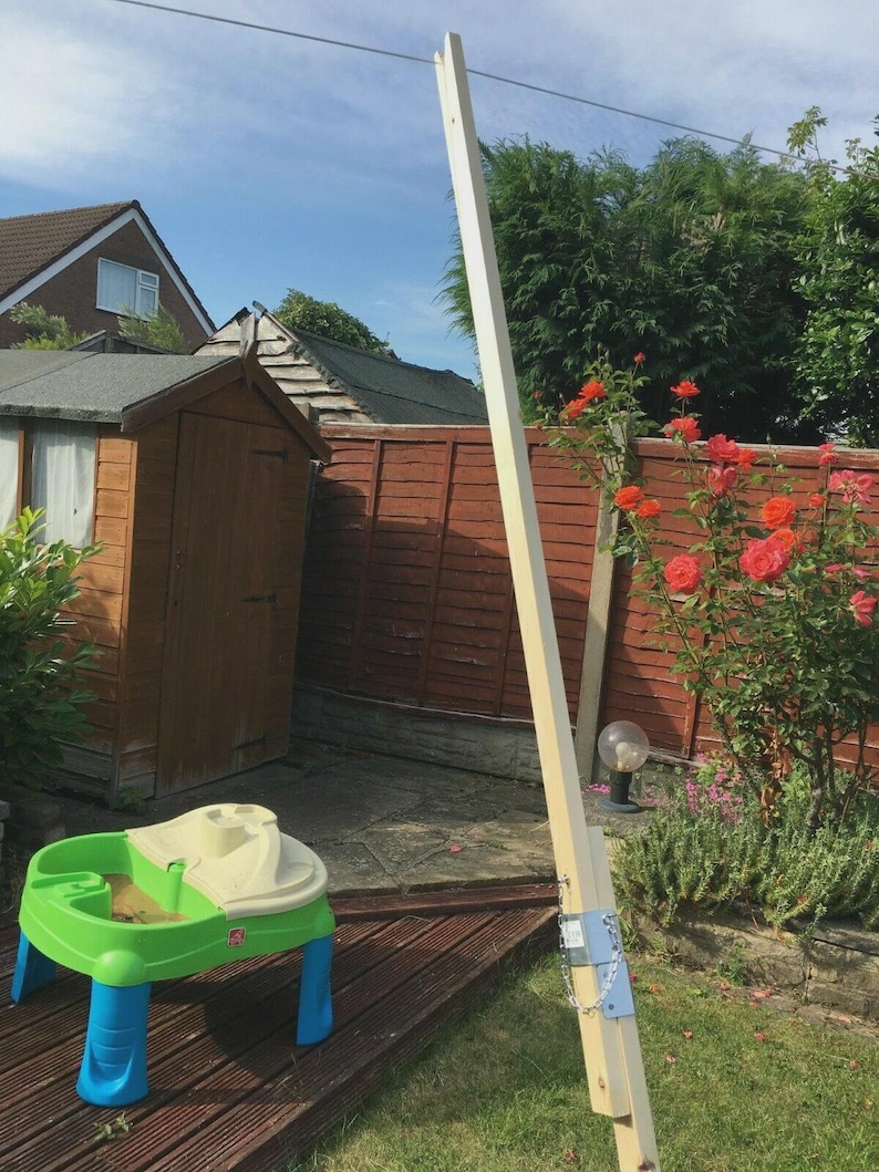 K&ouml;nnte beinhalten: Eine Gartenszene mit einer Holzspielstruktur und einem Sand- und Wassertisch. Die hellfarbige Holzstruktur ist mit Metallhalterungen befestigt. Der Tisch ist gr&uuml;n, blau und beige, perfekt f&uuml;r das Spielen im Freien.