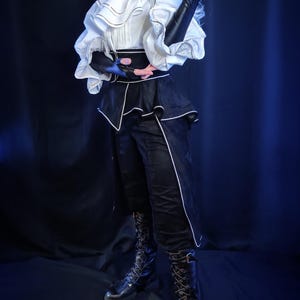 May include: A person wearing a white ruffled shirt with black accents, black pants with white trim, and black lace-up boots. The outfit has a Victorian-era aesthetic, with long black gloves and a high-collared shirt.
