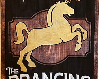 May include: A wooden sign for "The Prancing Pony Inn & Pub" with a gold horse silhouette. The sign features the text "The Best Beer in Bree" and "By Barliman Butterbur" in a rustic design.