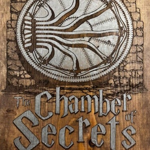 May include: Wooden sign with the text "The Chamber of Secrets" in a stylized font. The sign features a circular design with a mechanical or industrial aesthetic, and a brick-like border. The sign is made of stained wood.