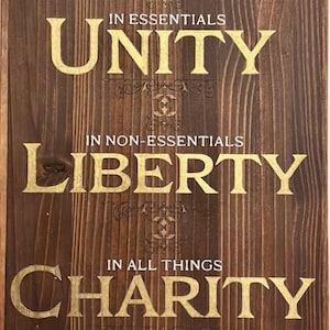 May include: Wooden sign with the words "UNITY", "LIBERTY", and "CHARITY" in gold lettering. The sign has a dark brown wood grain background. The text is arranged in three lines with decorative flourishes.