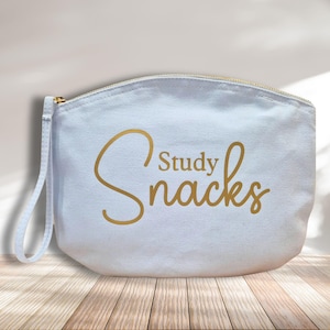 May include: A white canvas zippered pouch with a gold handle and the text "Study Snacks" in gold lettering.