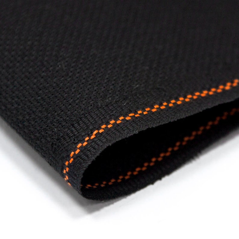 Peut inclure: Tissu noir avec une couture orange en zigzag le long du bord.