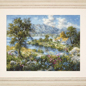 May include: Framed landscape art depicting a tranquil river scene with a tree, houses, and mountains. The artwork has a cream frame and shows a vibrant meadow with colourful flowers and lush greenery. The sky is blue with fluffy clouds, creating a peaceful vista.