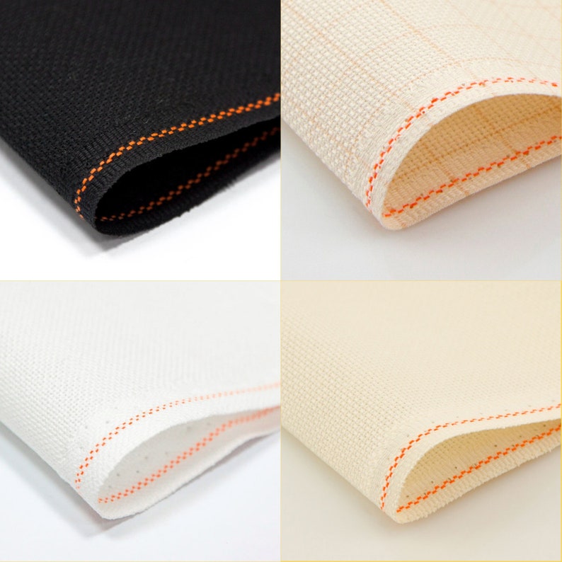 May include: Four samples of Aida cloth in different colors: black, beige, white, and ivory. Each sample is folded in half and has an orange stitched edge.
