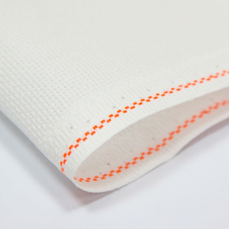 Peut inclure: Tissu Aida blanc avec une bordure cousue orange. Le tissu est pli&eacute; en deux, montrant les coutures des deux c&ocirc;t&eacute;s.