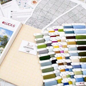 May include: A cross-stitch kit from the Gold Collection by Luca-S, depicting a landscape scene. The kit includes a box with the design image, a canvas, a variety of coloured embroidery floss, and pattern charts. The floss colours range from blues and greens to yellows and browns.