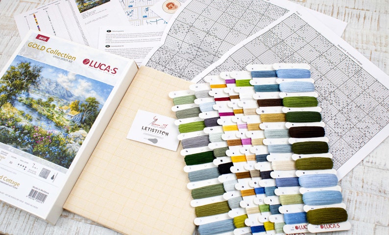 May include: A cross-stitch kit from the Gold Collection by Luca-S, depicting a landscape scene. The kit includes a box with the design image, a canvas, a variety of coloured embroidery floss, and pattern charts. The floss colours range from blues and greens to yellows and browns.