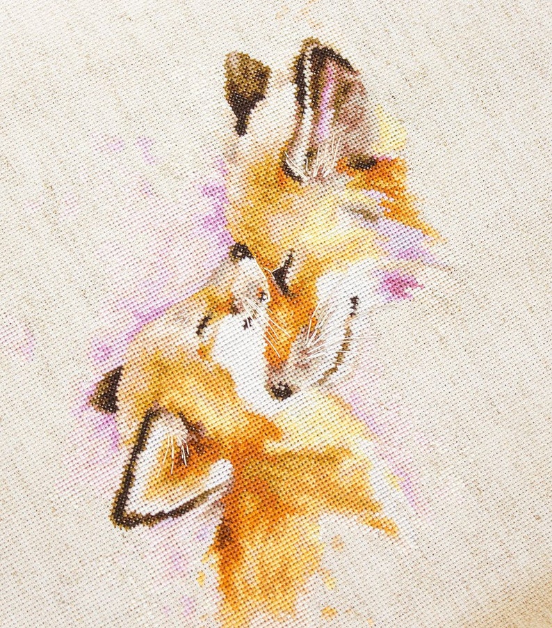 May include: Cross-stitch embroidery depicting two foxes cuddling, with a watercolour-like effect in shades of orange, brown, and pink.