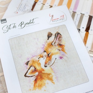 May include: Cross stitch pattern featuring two foxes cuddling, with a pink and white background. The pattern is titled "Set de Brodat" and is part of the "Quality Premium Line" by Luca-S.
