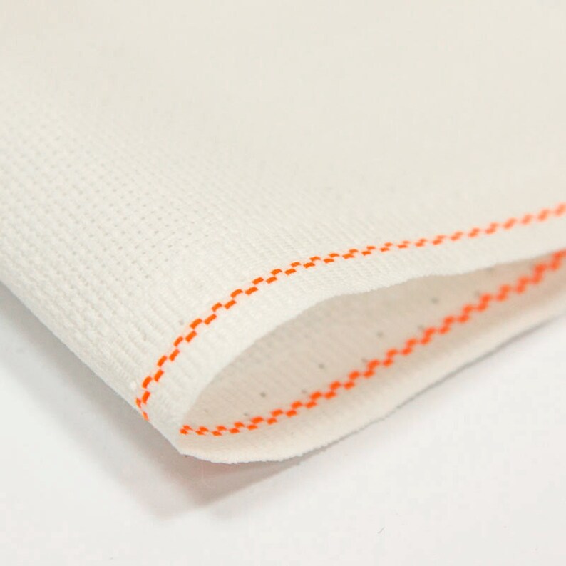 Peut inclure: Gros plan sur un tissu blanc avec un bord cousu orange. Le tissu a une texture fine et tiss&eacute;e.