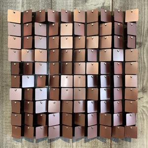 May include: A wall covered in a grid of small, square, metallic sequins. The sequins are a light brown color and have a slightly iridescent sheen.