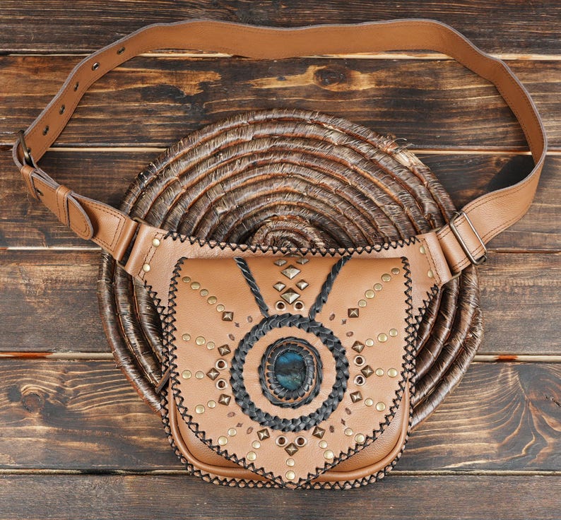 Handmade tan leather waist belt bag with labradorite gemstone centerpiece and black braided detailing.
