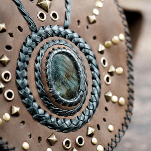 leather waist pouch with gemstone inlay, black lacing, and flap closure.