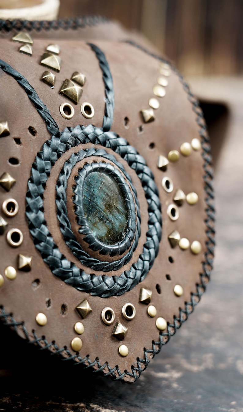 leather waist pouch with gemstone inlay, black lacing, and flap closure.