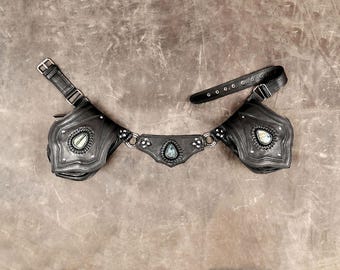 May include: A black belt featuring two attached pouches and a central decorative panel. Each pouch and the centre piece are adorned with a single teardrop-shaped iridescent stone, silver-toned metal studs, and circular metal rings.
