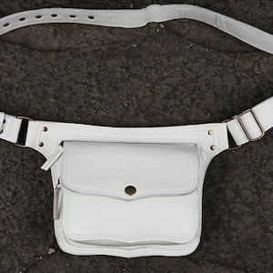 white leather waist bag showing front flap closure with metal snap button and zipper pocket for boho summer festival style.
