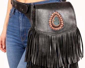 May include: Black leather fanny pack with a decorative turquoise stone and copper-colored woven trim. The bag features long fringe and a belt. A stylish accessory for carrying essentials.