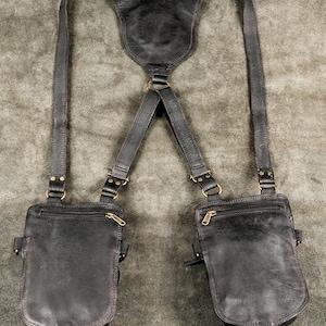 Plain rear finish of black dual holster pouches showing hidden zippered security pockets and smooth harness straps.