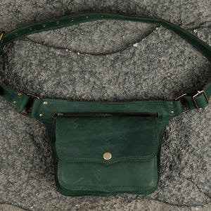 Olive green leather hip bag with flap snap pocket, front zipper compartment, and adjustable waist strap for unisex travel utility.