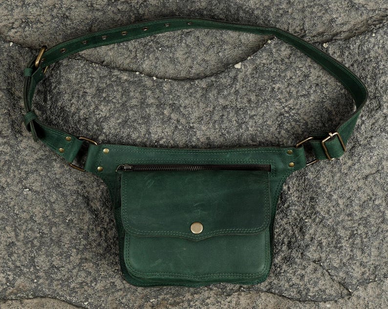 Olive green leather hip bag with flap snap pocket, front zipper compartment, and adjustable waist strap for unisex travel utility.