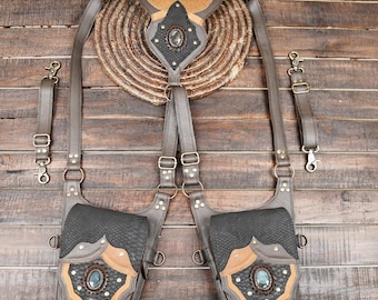 May include: A dual-pouch harness system featuring dark gray and tan leather-like panels with textured snake-skin patterns. Each pouch is adorned with a central iridescent oval stone, brass-toned rivets, and adjustable straps with metal buckles.