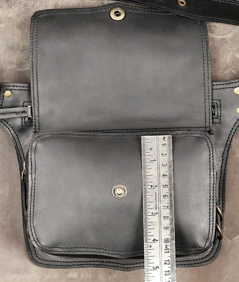 Black handmade leather hip bag shown open with a ruler measuring the front pocket height at 5 inches (13 cm)

leather hip bag, utility belt bag, festival hip bag, drop leg bag, thigh holster bag, steampunk hip pouch, black waist bag, handmade belt purse, biker thigh pack, gothic waist pouch, rave utility pack, leather fanny pack, burning man gear