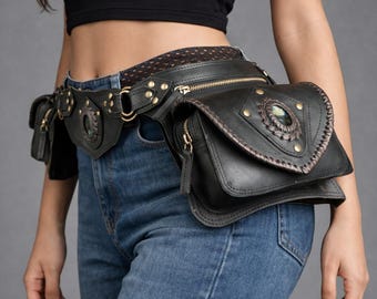 May include: Black leather fanny pack with multiple compartments, decorative studs, and a large central gemstone. The belt bag is worn around the waist and features a zipper closure and intricate stitching details.