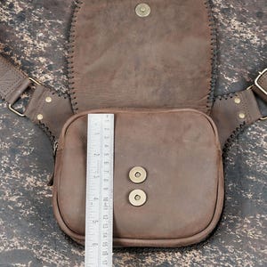 Festival-style gemstone waist bag with tan leather finish and braided black trim.