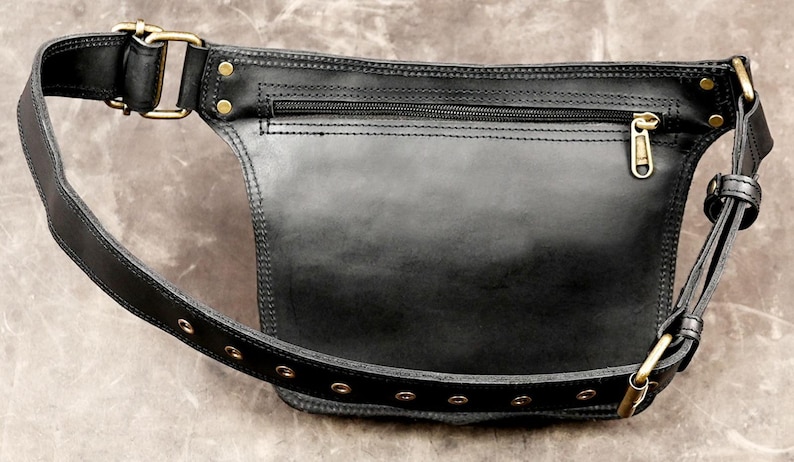 Back view of a handmade black leather hip bag with a hidden security zipper pocket, antique brass hardware, and an adjustable eyelet belt strap.

leather hip bag, black waist pouch, festival belt bag, utility hip pouch, steampunk waist bag, boho fanny pack, handmade leather bag, travel waist pack, gothic hip bag, leather fanny pack, rave utility belt, brass hardware bag, biker waist bag