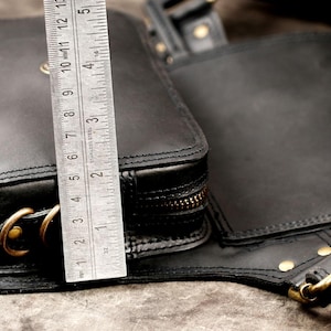 Side view dimension check of handmade black leather hip pouch with metal ruler showing pocket depth and height capacity.