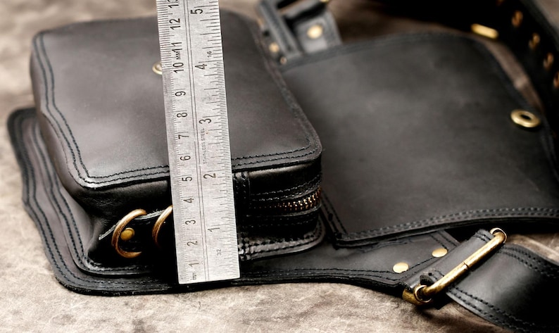 Side view dimension check of handmade black leather hip pouch with metal ruler showing pocket depth and height capacity.