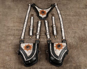 May include: A harness featuring two pouches with a snakeskin pattern, black leather trim, and bronze-toned metal hardware. The design includes a central triangular piece and two smaller detachable straps, all accented with sun-shaped emblems.