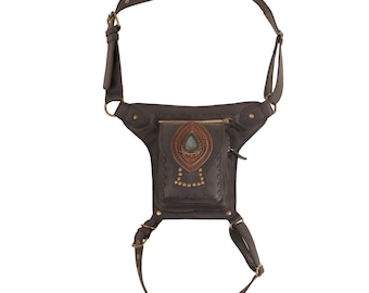 Puede incluir: Bolso de cadera de cuero marrón oscuro con correas ajustables y un bolsillo delantero decorativo. La bolsa presenta una piedra preciosa central y tachuelas de color latón. Dimensiones: 25 cm de ancho y 30 cm de alto.