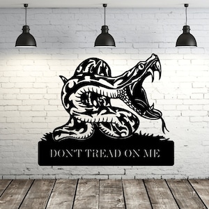 May include: Black and white silhouette of a coiled snake with its mouth open, with the text "Don't Tread On Me" below. The image is on a white brick wall background.