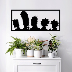 Puede incluir: Silueta en blanco y negro de la familia Simpson, Homer, Marge, Bart y Lisa, en un marco rectangular en una pared blanca. El marco está en un estante blanco con plantas en macetas.