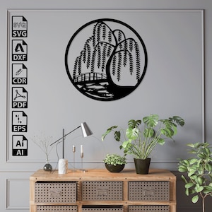 May include: Black and white silhouette of a weeping willow tree with a bridge over a pond in a circle. The image is on a gray wall with a wooden dresser with three drawers underneath. There are two plants on the dresser.