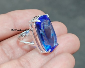 May include: A silver ring featuring a large, rectangular, blue gemstone. The ring is set in a prong setting and has a simple band.
