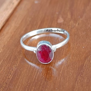 May include: A silver ring with a red oval gemstone. The ring is engraved with the text "Asilverhills".