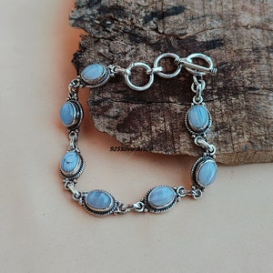 May include: A silver bracelet with a toggle clasp and six oval-shaped blue agate stones.