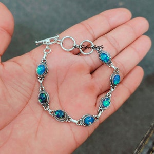 May include: A silver bracelet with a toggle clasp and six oval-shaped blue opal stones.