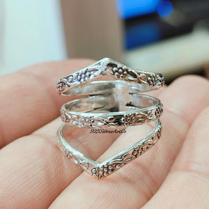Op de afbeelding: Zilveren ring met een drievoudig bandontwerp met een bloemenpatroon. De ring is open en verstelbaar om te passen op verschillende vingermaten. 925SilverArtCo is op de ring gedrukt.