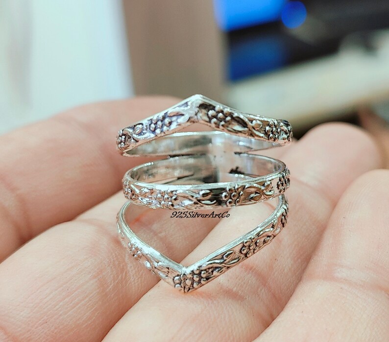 Op de afbeelding: Zilveren ring met een drievoudig bandontwerp met een bloemenpatroon. De ring is open en verstelbaar om te passen op verschillende vingermaten. 925SilverArtCo is op de ring gedrukt.